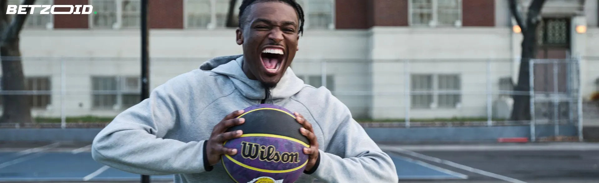 Excited basketball player holding a ball, representing the energetic sports culture covered by BC sportsbooks.