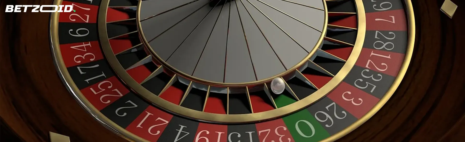 Close-up view of a casino roulette wheel with alternating red and black numbered slots and a white ball resting in one section.
