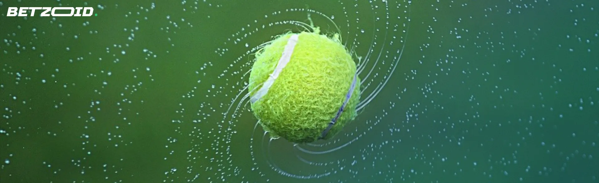 Tennis ball in motion in the air with water drops.