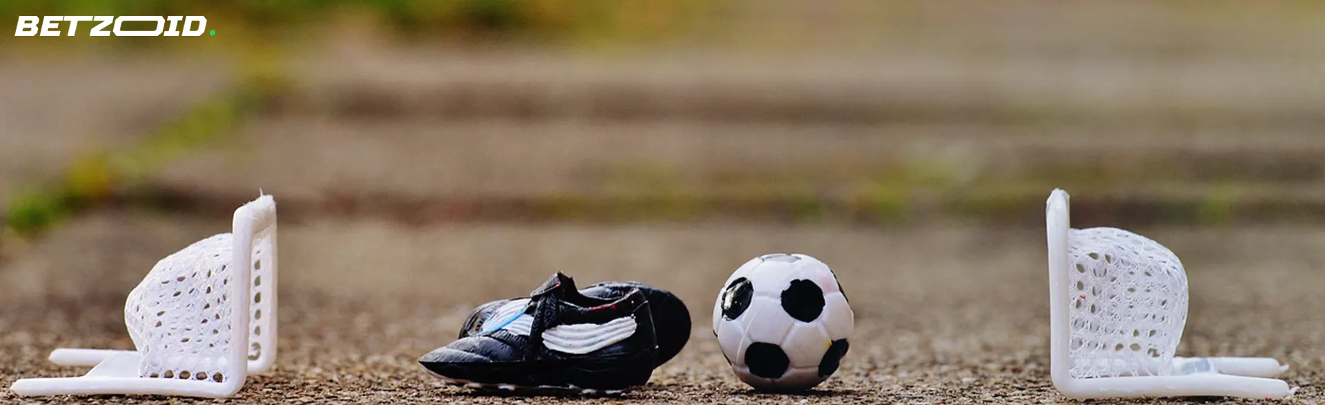 A miniature soccer set with a ball, shoes, and net on a ground.