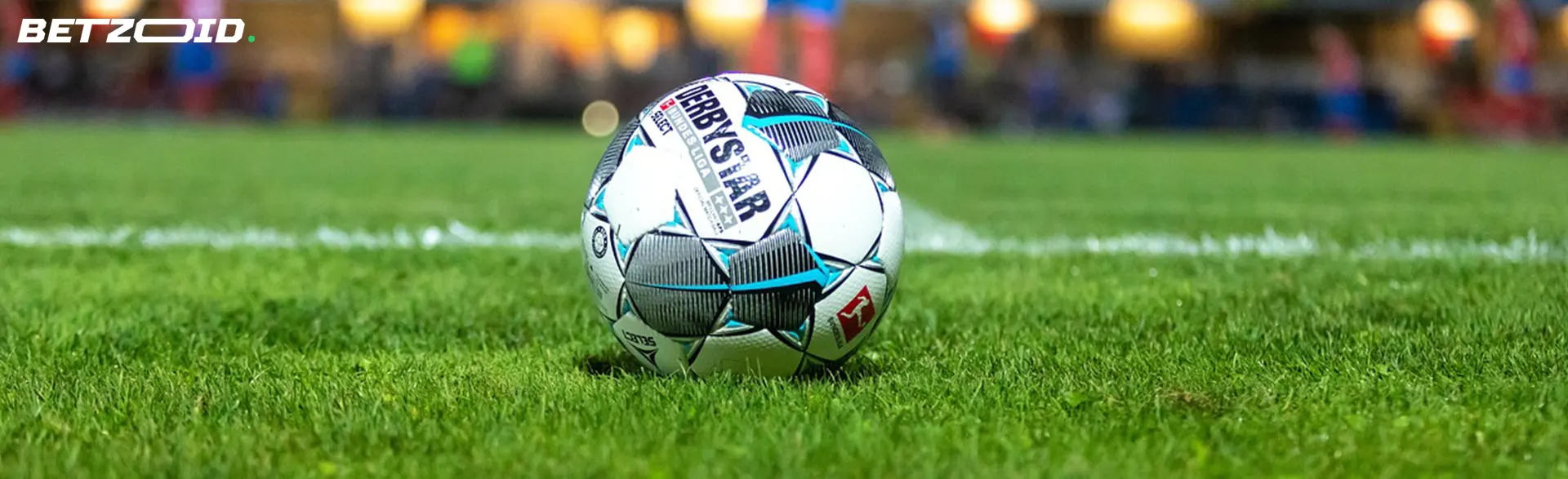 A soccer ball on the grass in a stadium.