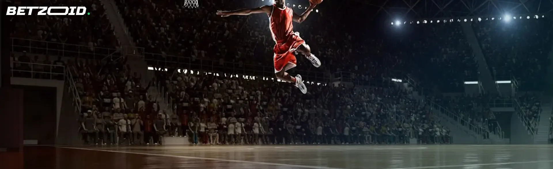 A basketball player in a red uniform performing a slam dunk during a game, with a crowd watching in a well-lit indoor arena.