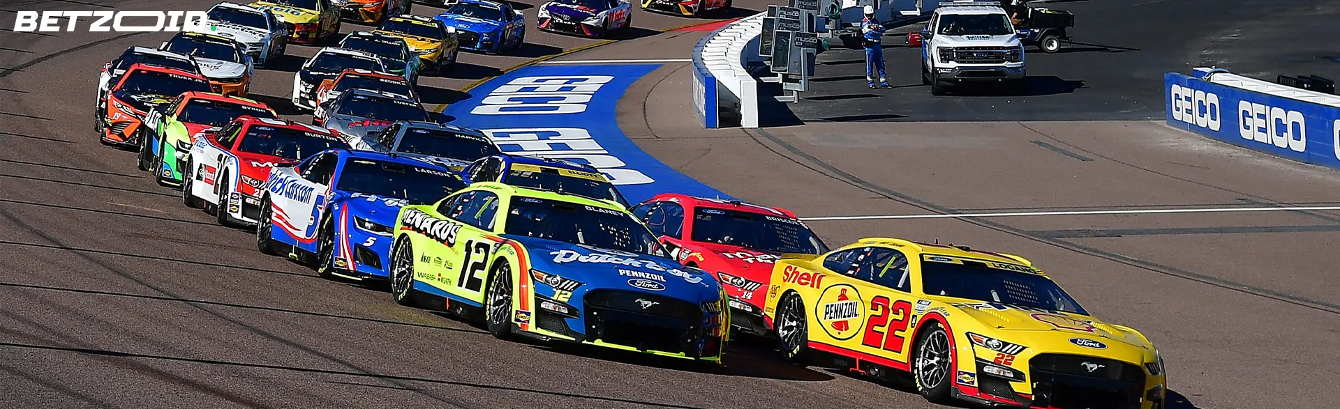 Dynamic NASCAR race depicting a close pack of colorful cars at a turn, illustrating the fast-paced action available on in-play betting sites in Canada.