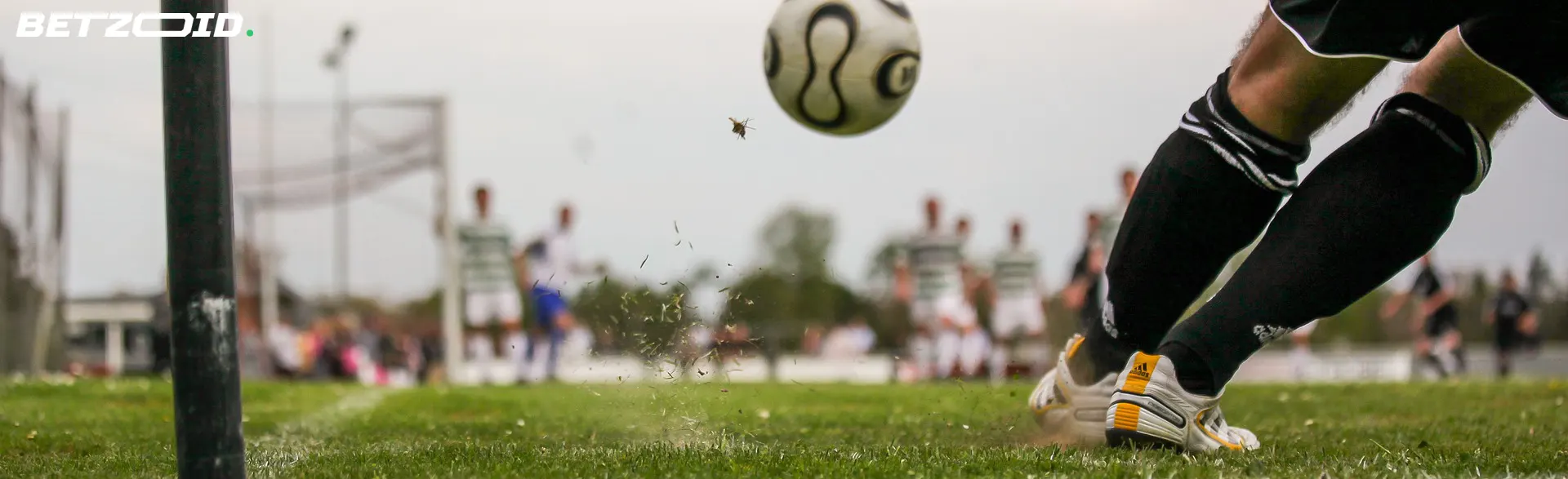 Soccer player kicking a ball on a grass field, highlighting online bookie with cash-out feature for soccer bets.