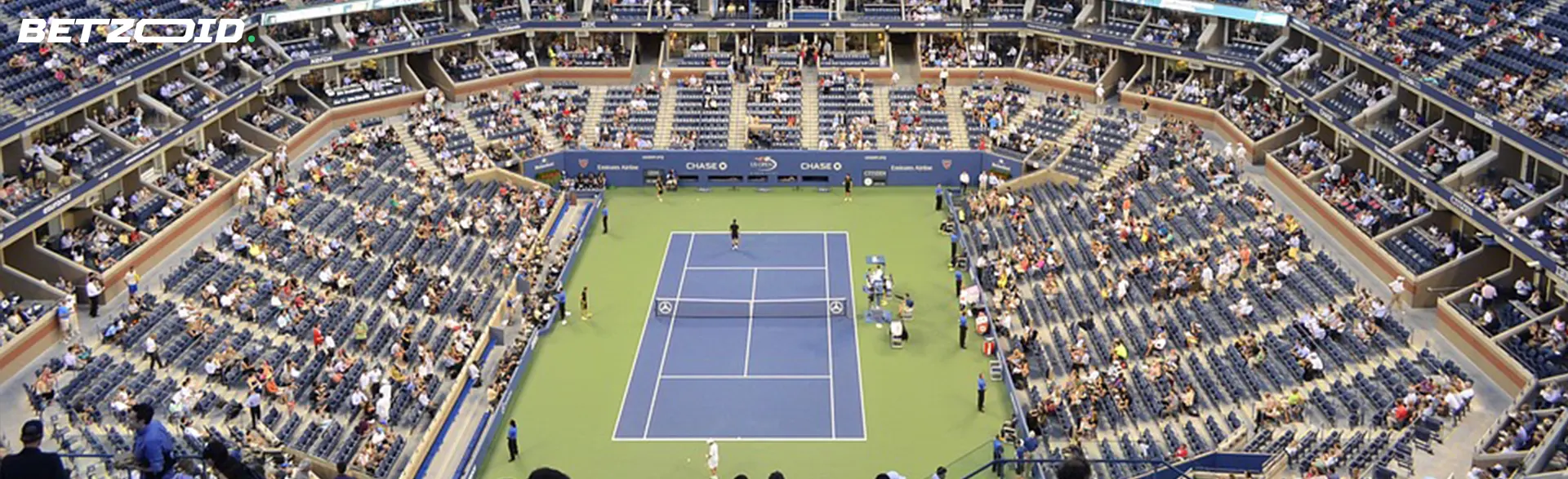 Overhead view of a tennis tournament at a large stadium, with spectators and players during a match.