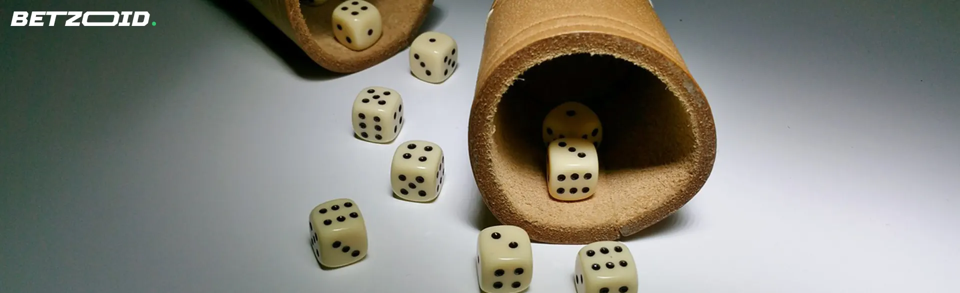 Several dice spilling out of two leather dice cups onto a smooth surface.