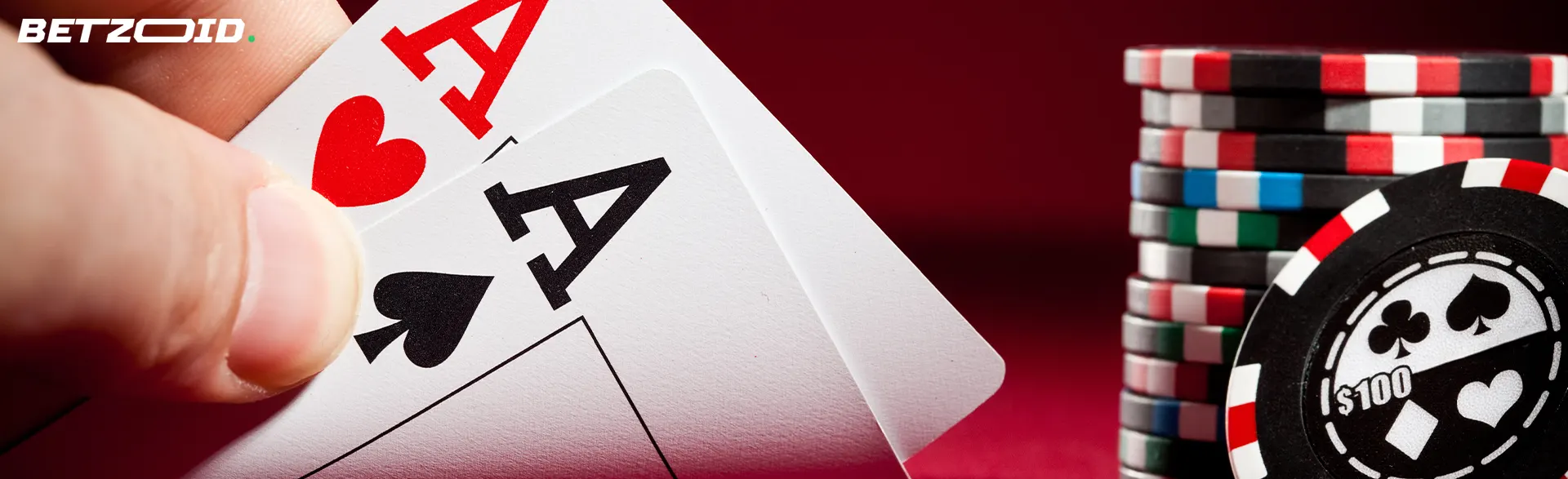 Due assi in mano, fiches da poker accanto.