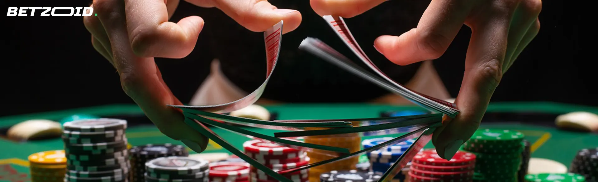A player shuffles cards over a table with poker chips.