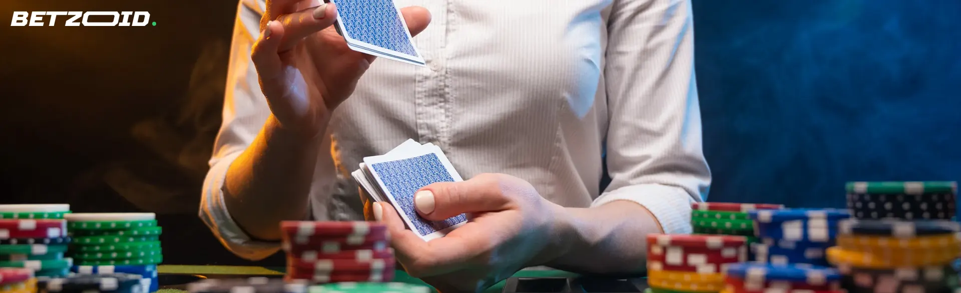 Un hombre baraja cartas, hay montones de fichas cerca.
