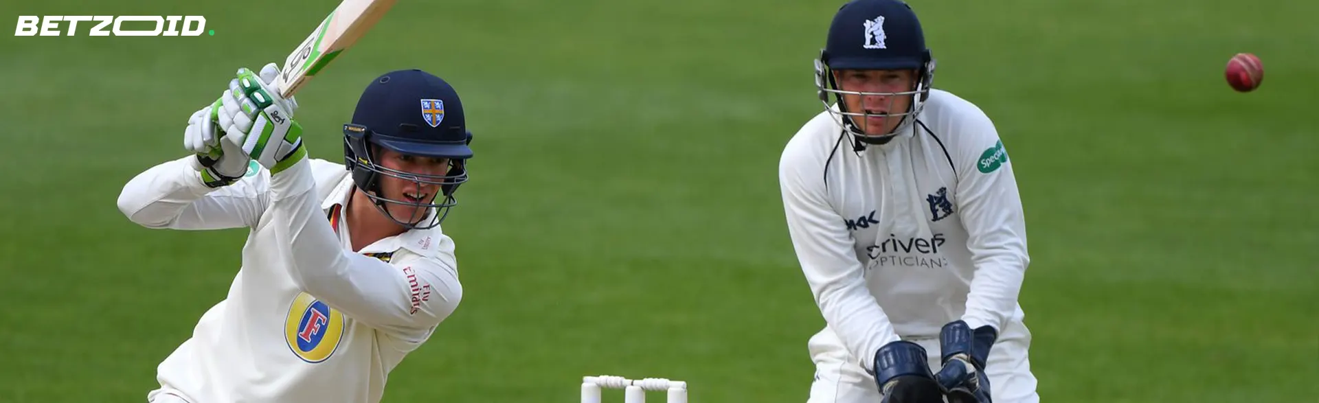 A cricketer hits the ball during a game.