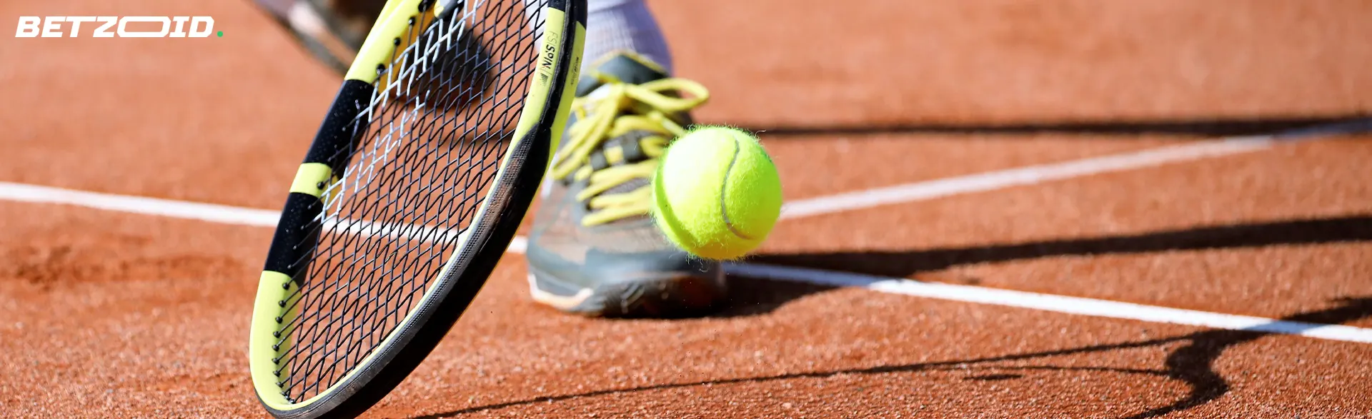 Tennis ball near the racket on the court.