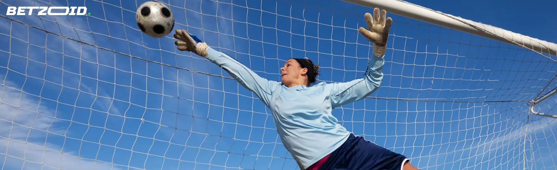 The goalkeeper is trying to catch the soccer ball.