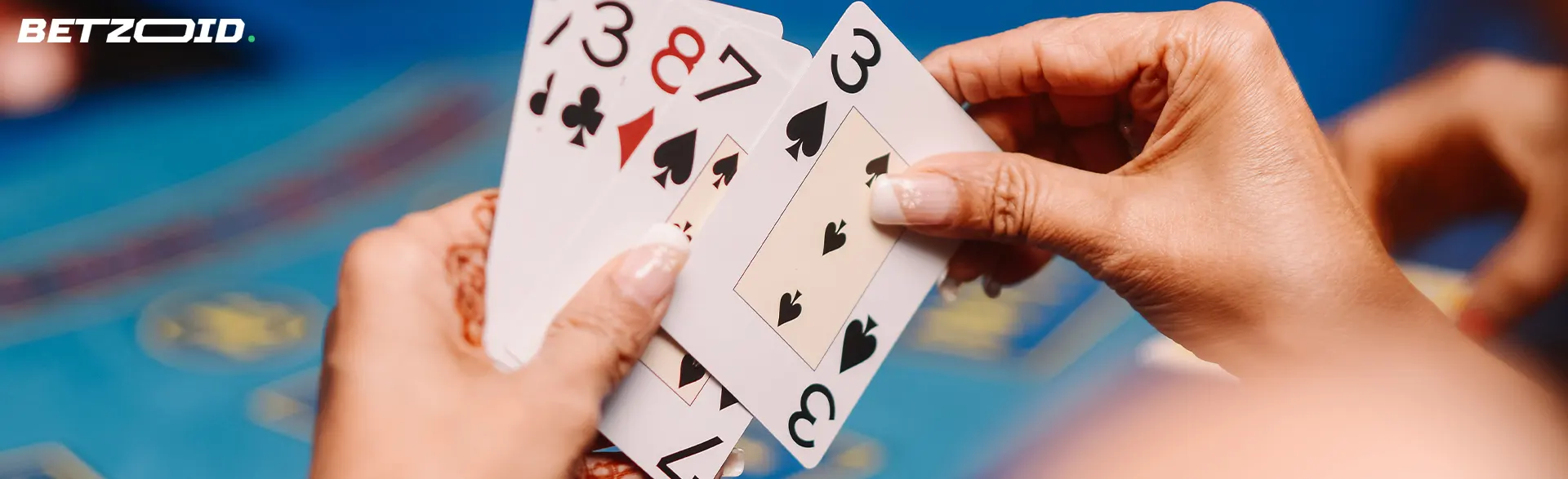 O jogador segura as cartas contra o fundo da mesa do casino.