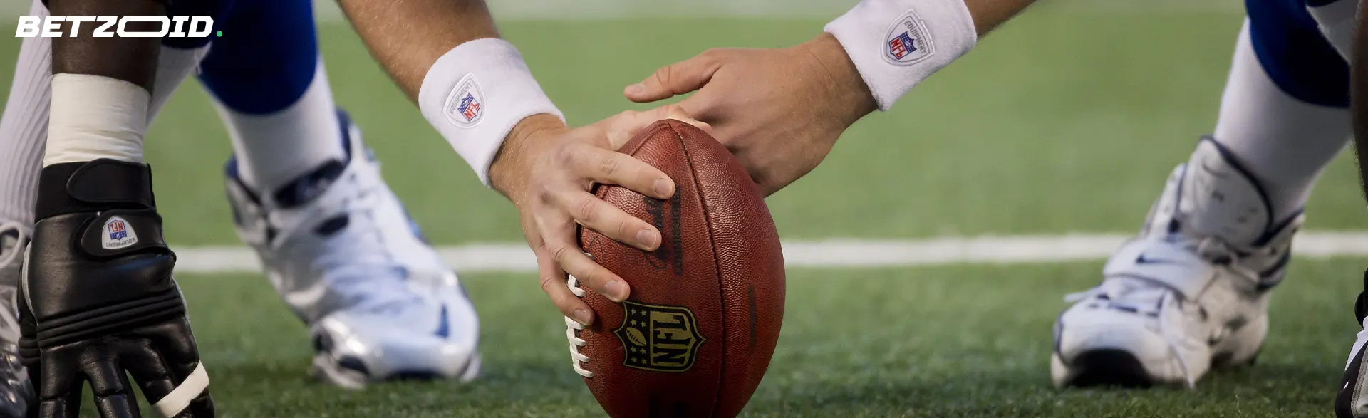 American-Football-Spieler hält den Ball auf dem Rasen.