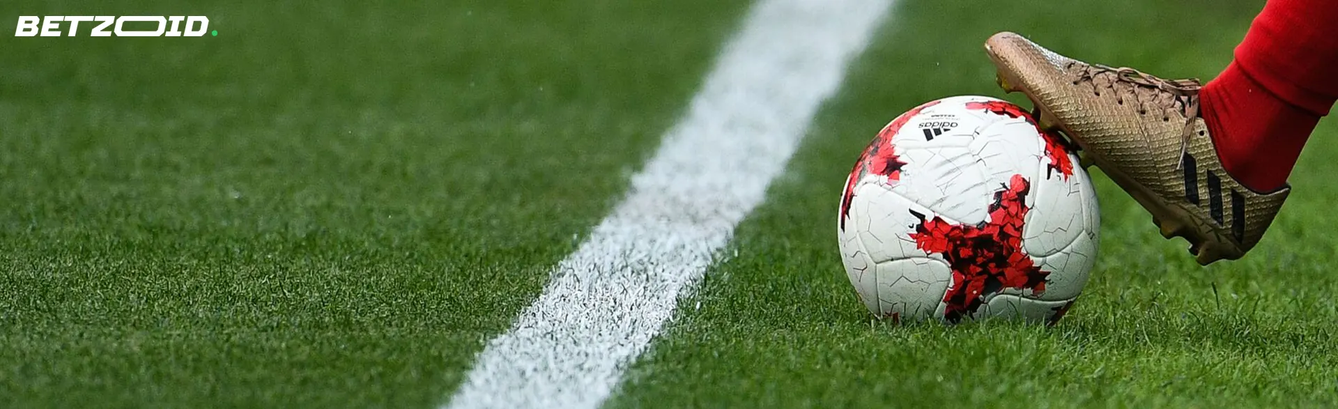 A football player's foot holds the ball on the field.