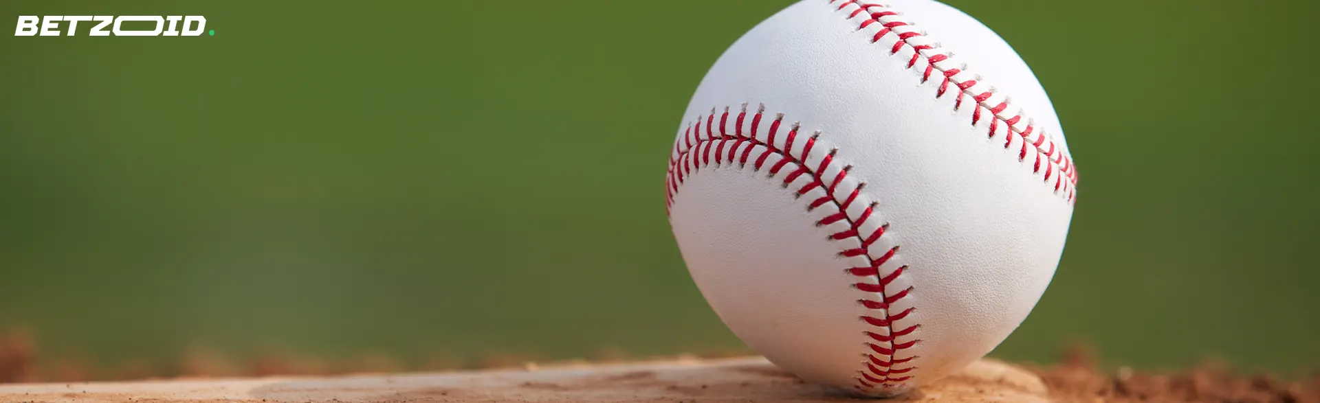 Uma bola de basebol está caída na relva.