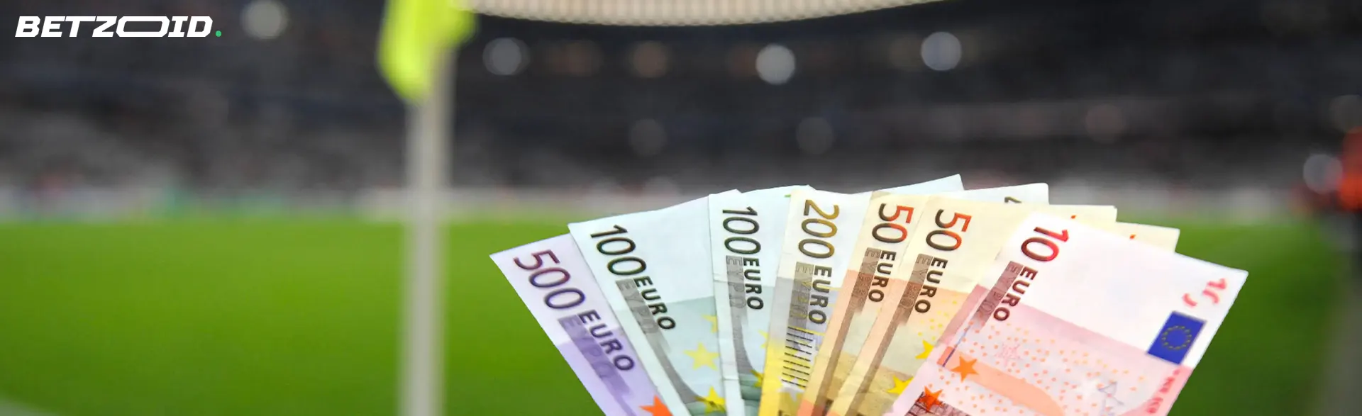 Euro-Scheine vor einem Fußballplatz.