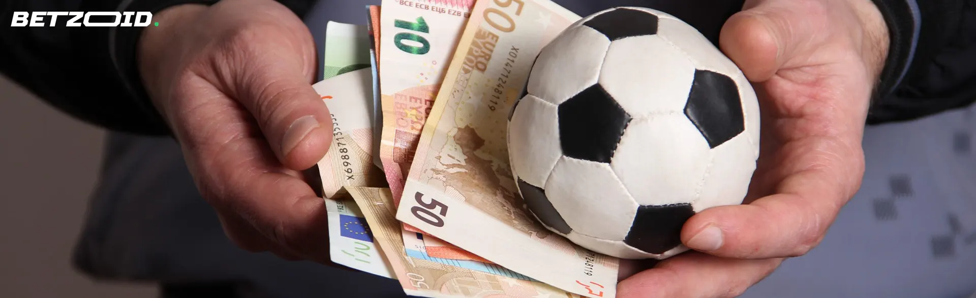 Euro-Banknoten und ein Fußball in Menschenhand.