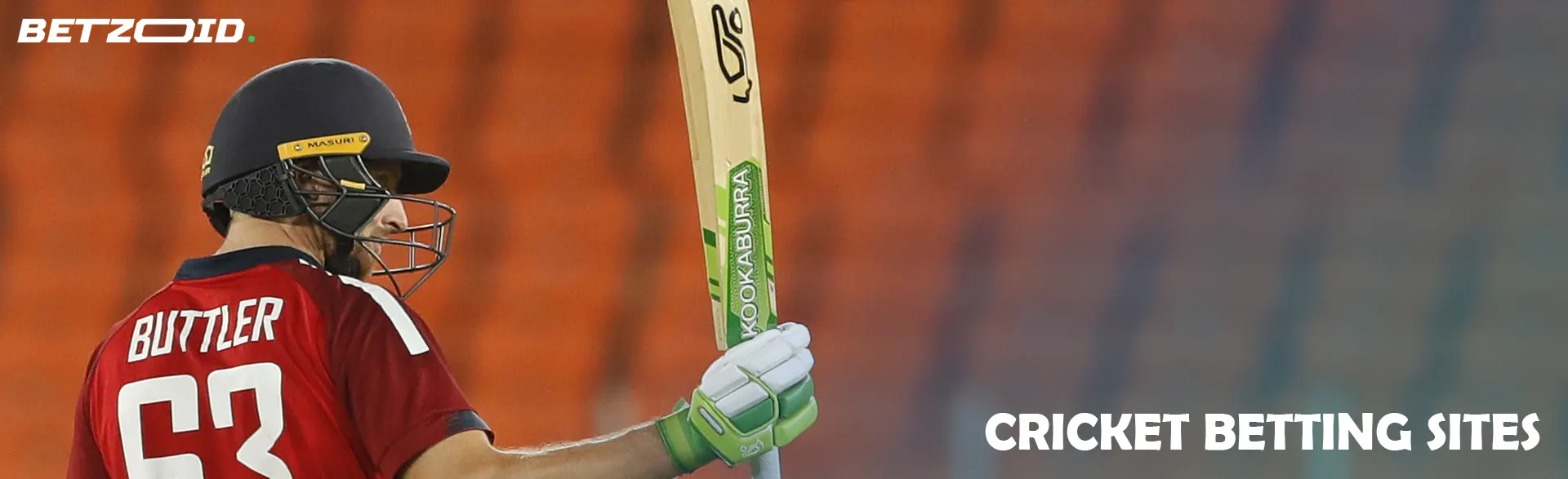 A cricketer with a bat against the background of empty stands.