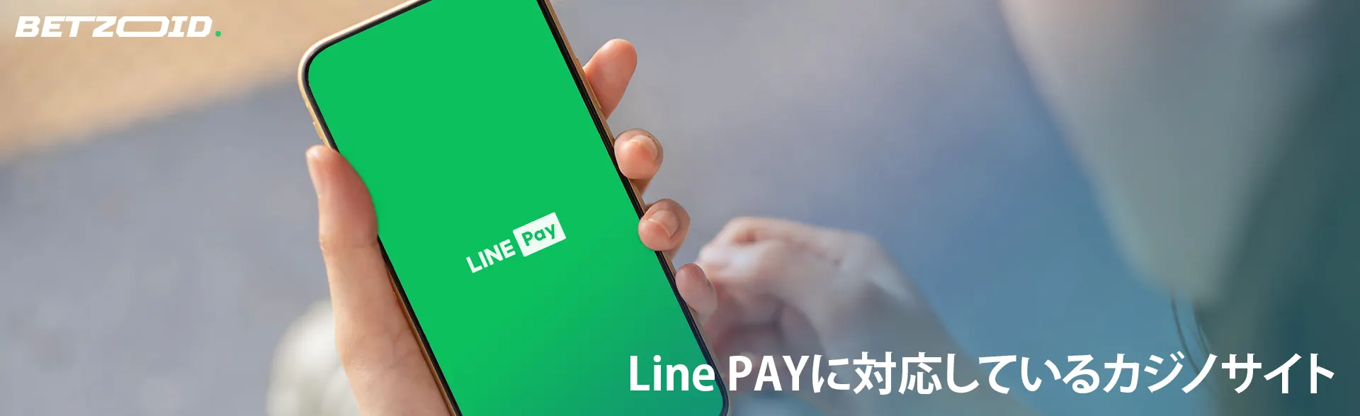 Line PAYのロゴが付いた電話を持つ男性。