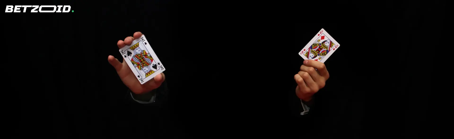 A man holds two cards on a dark background.