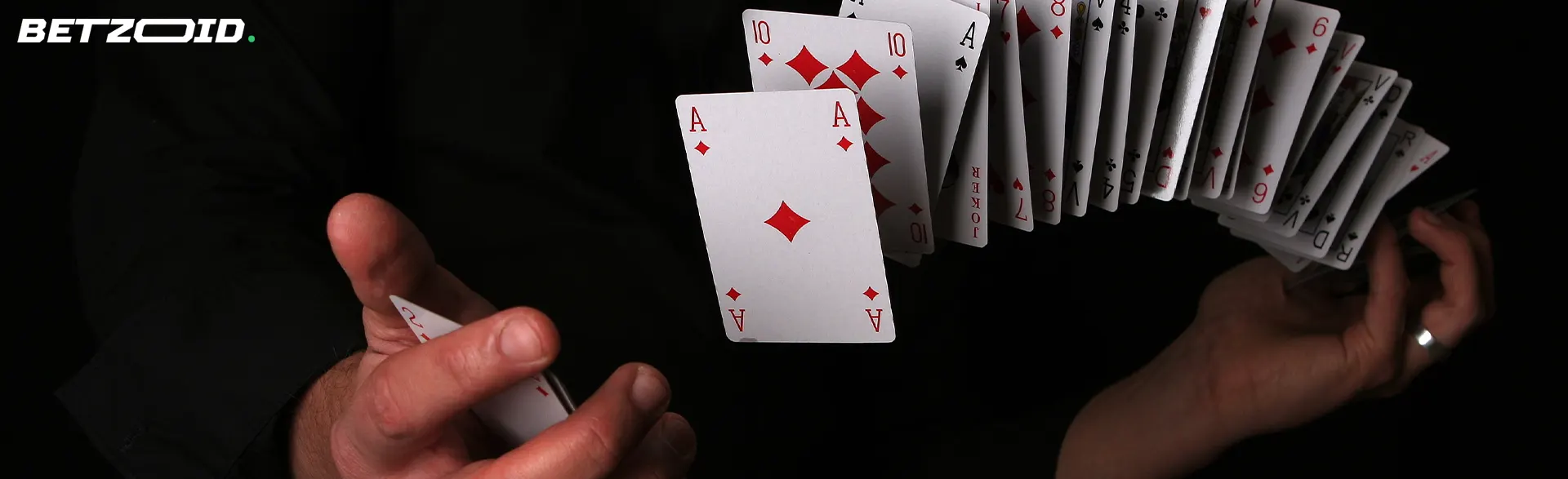 A man shuffles cards on a dark background.