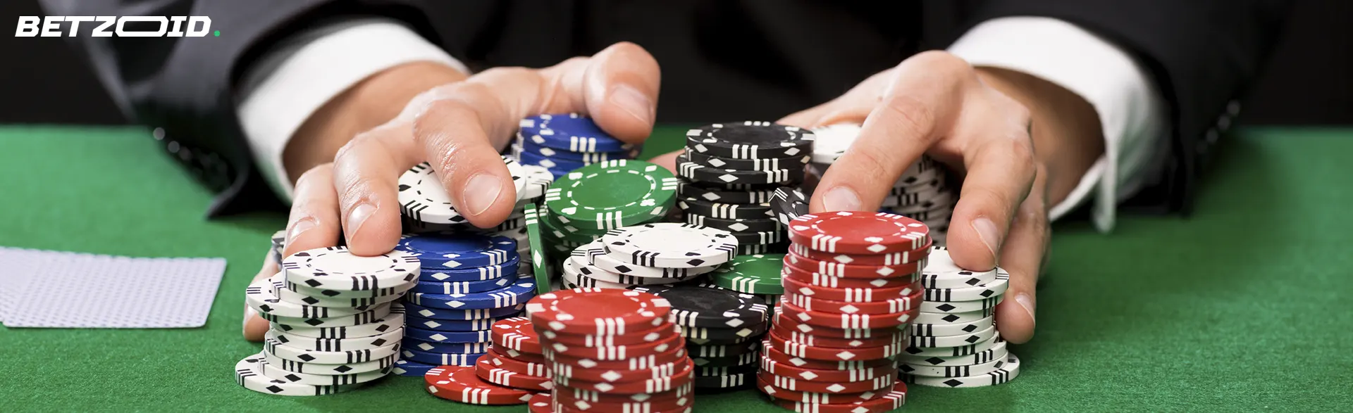 A player holds a pile of chips on a casino table.