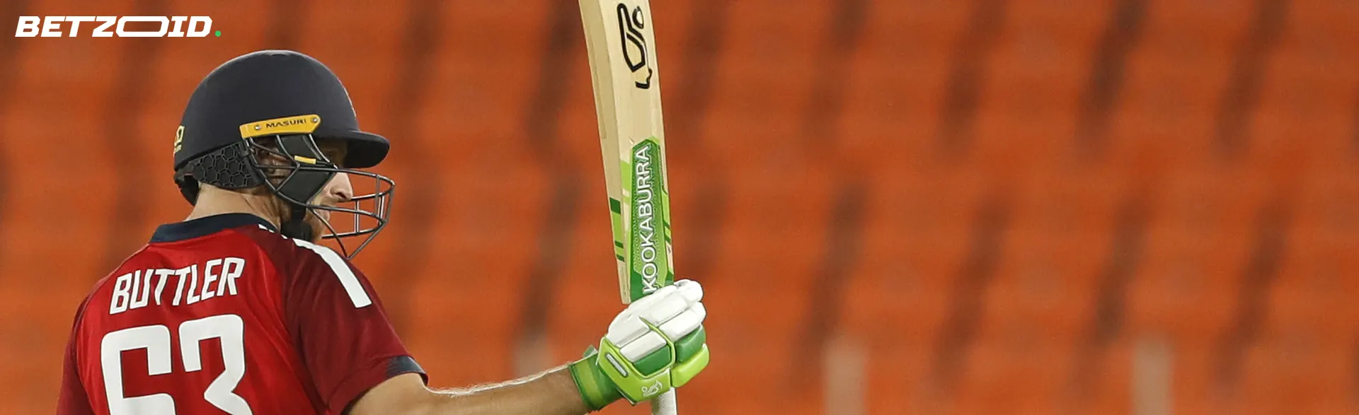 Cricketer with bat against the backdrop of stands.