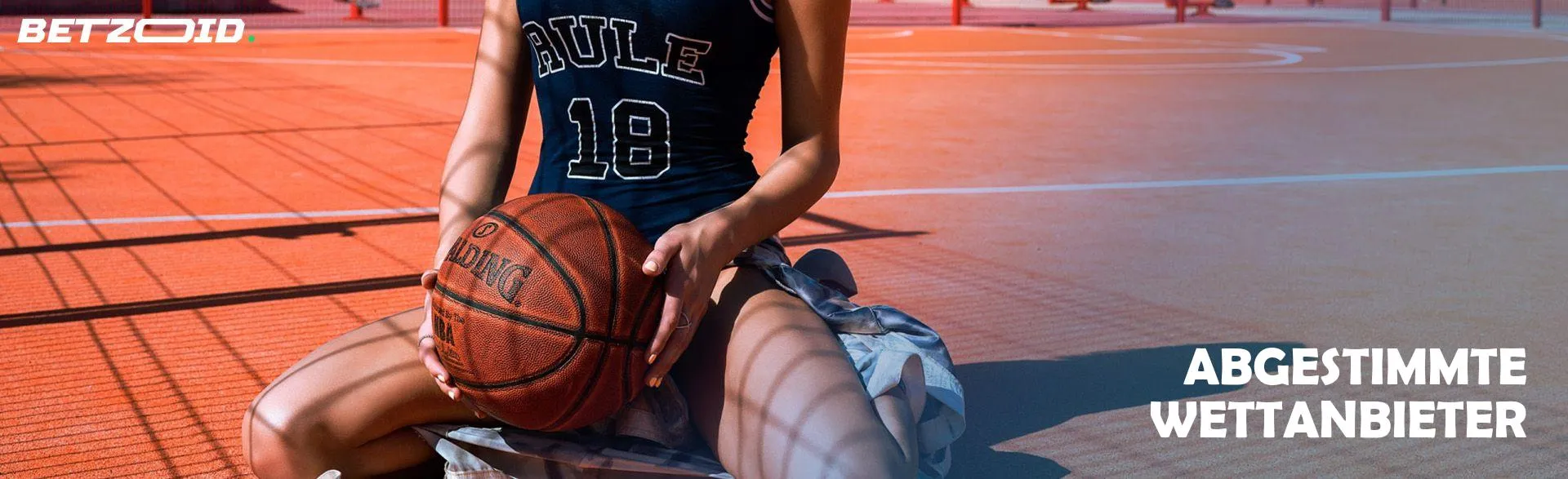Ein Basketballspieler sitzt mit einem Ball.