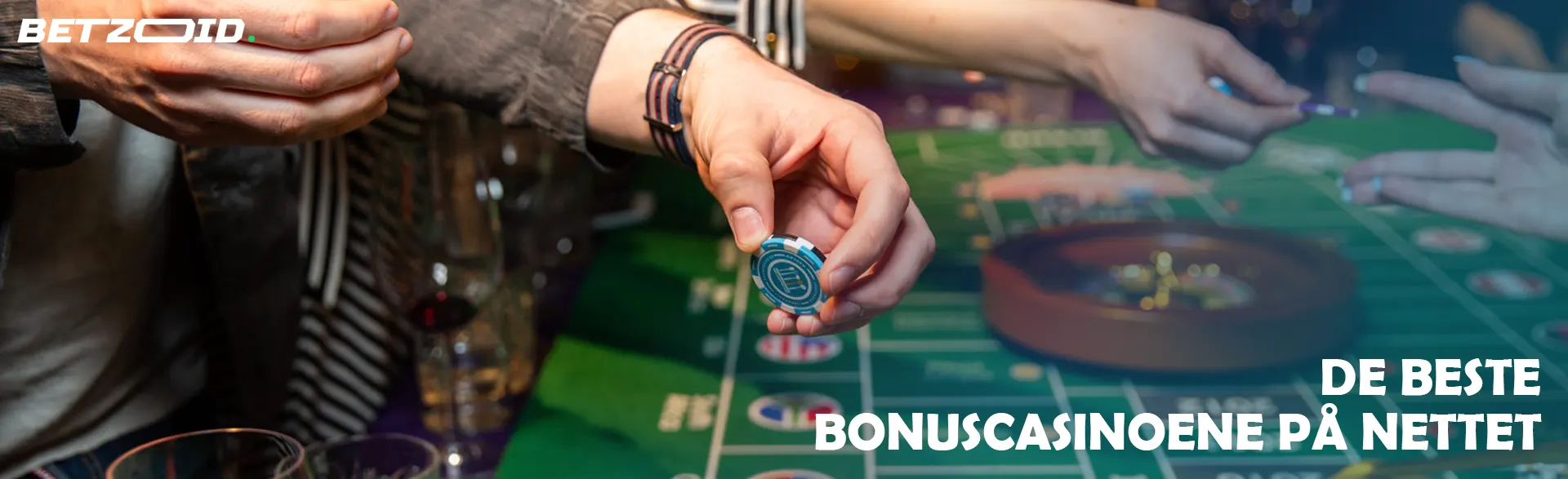 En spiller holder sjetonger over et rulettbord.