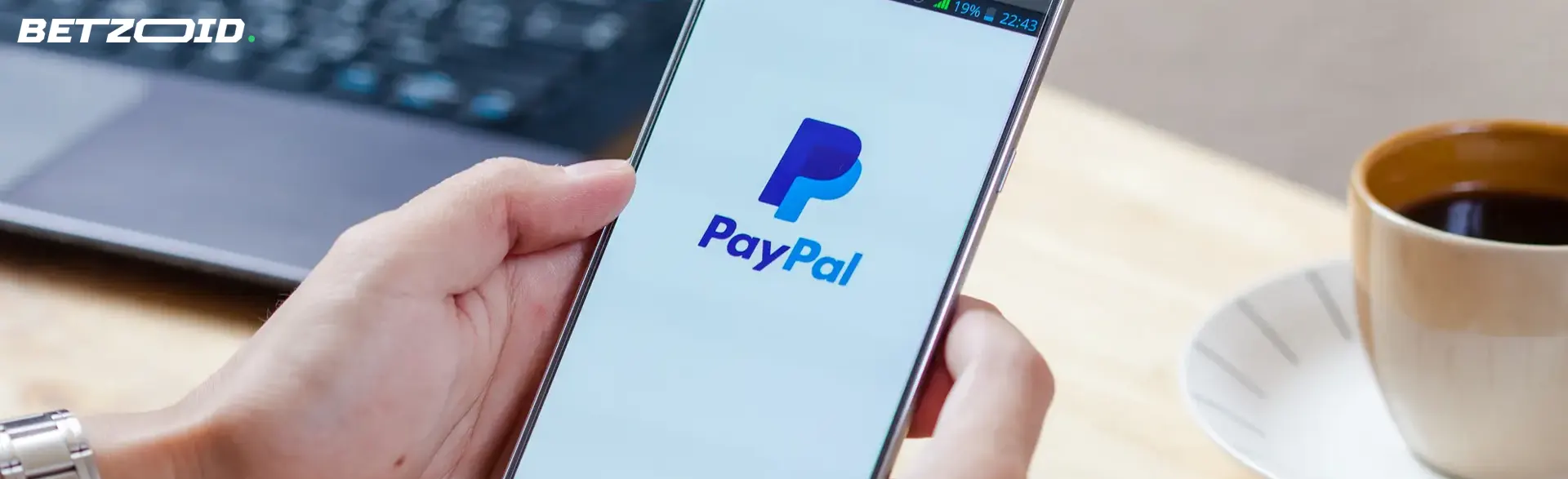 Smartphone med PayPal-logotypen i mänskliga händer.