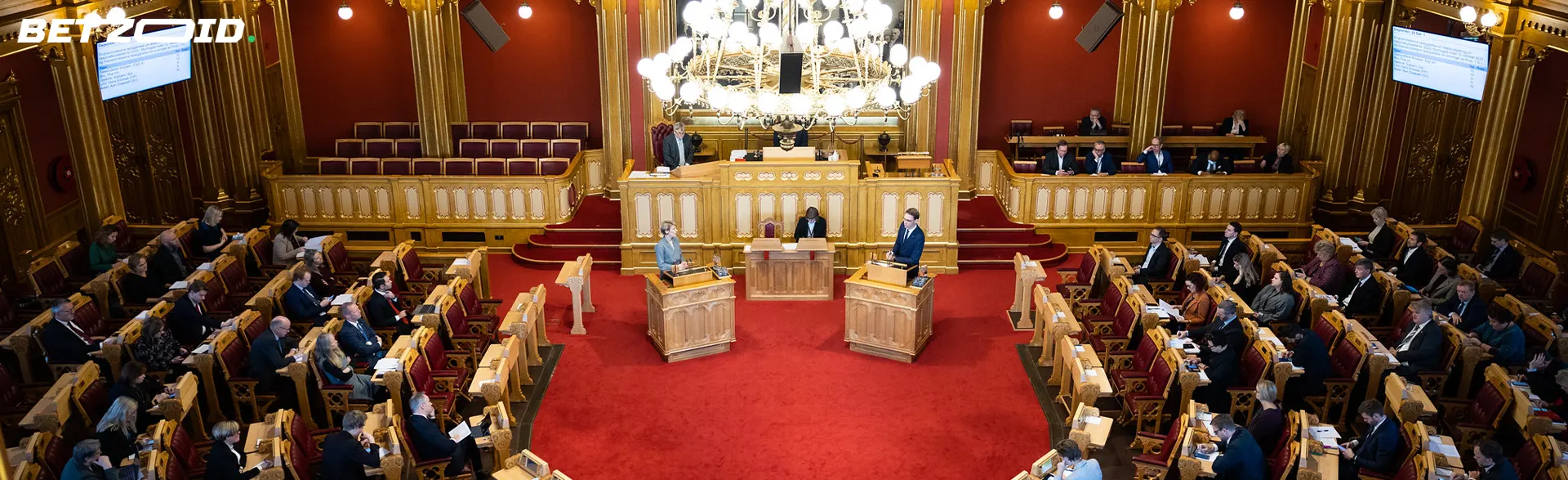 Stortingsmøte i en stor sal med rød løper.