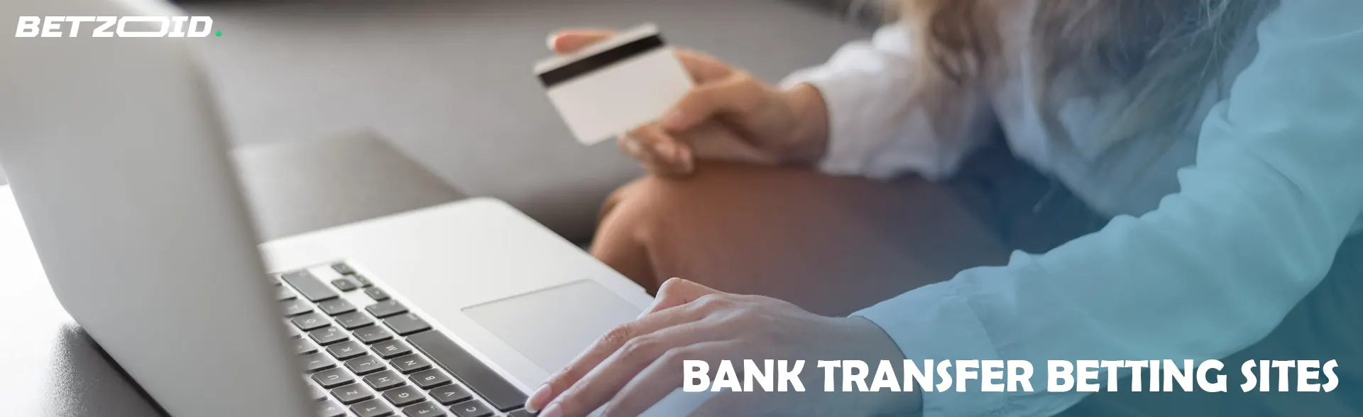 Woman holding a bank card next to a laptop.