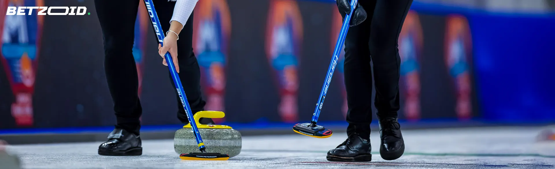 Two curlers are pushing a rock onto the ice.
