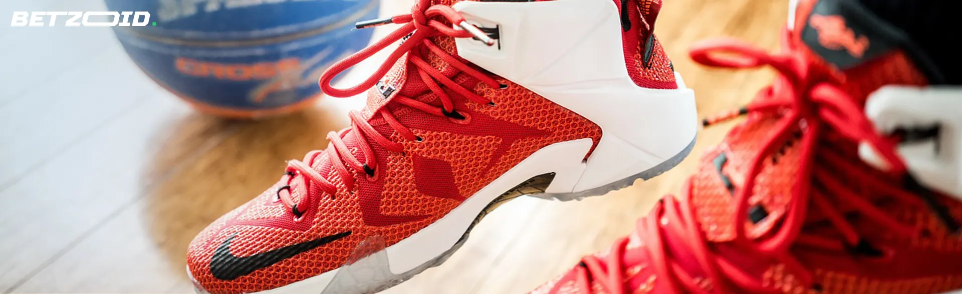 Red basketball sneakers and ball on the floor.