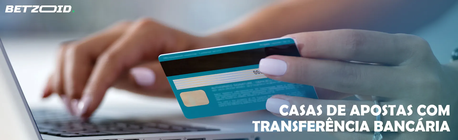 Mulher segurando um cartão bancário ao lado de um laptop.