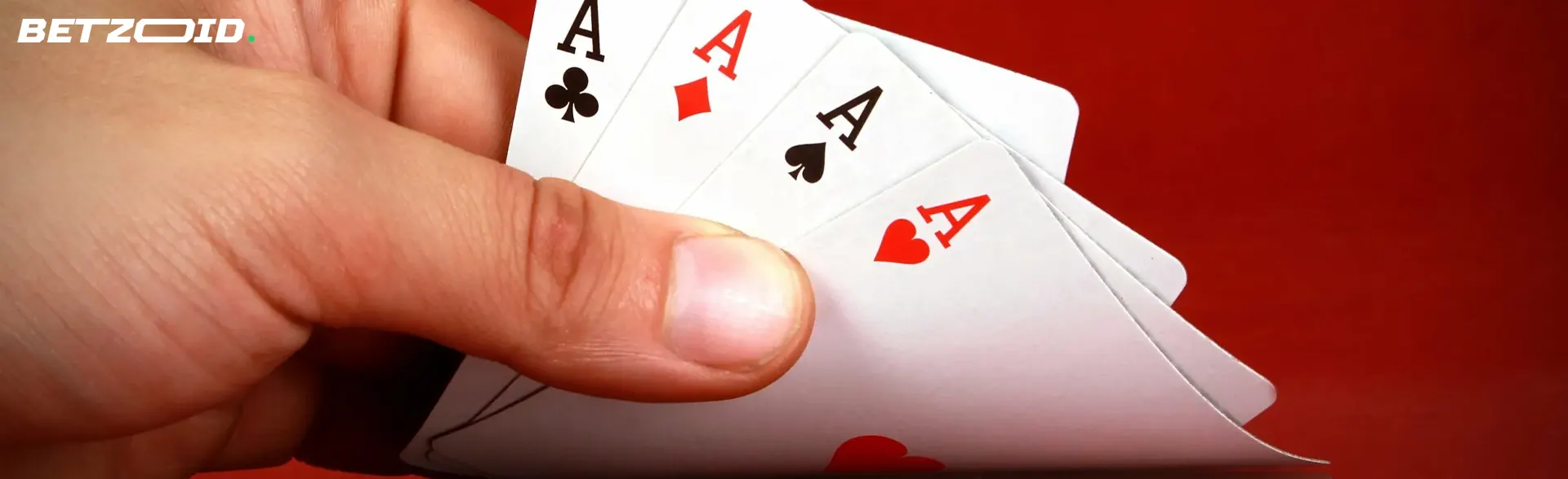 Cartas en la mano de un jugador sobre un fondo rojo.