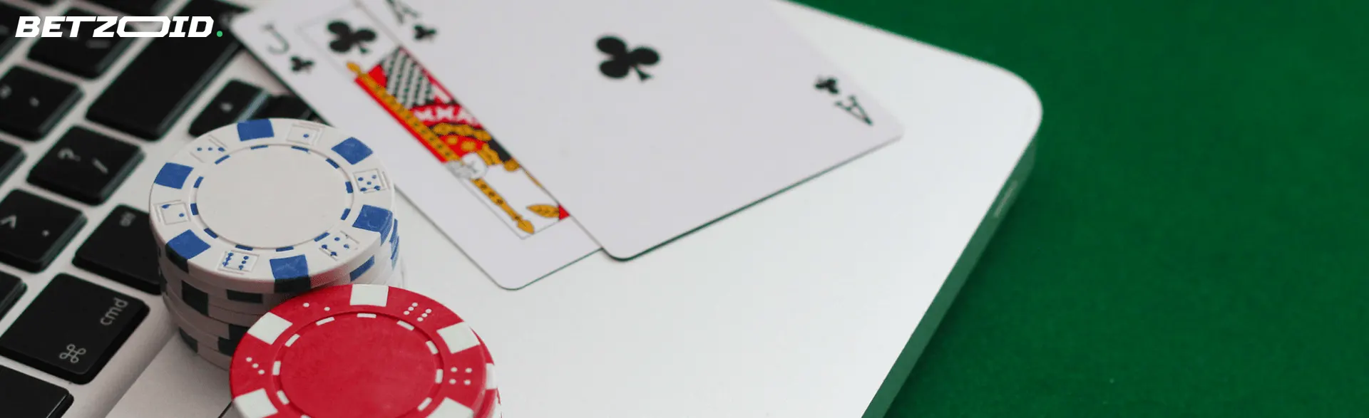 Auf einem Laptop liegen Spielkarten und Pokerchips.