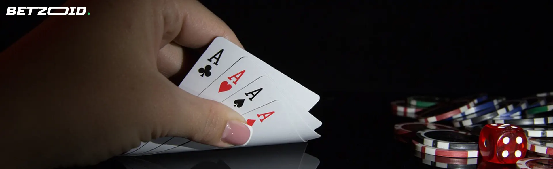 La main d'un homme tient des cartes à côté des jetons de casino.