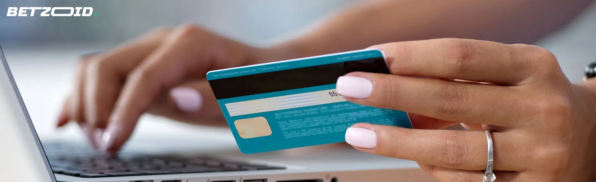 Une fille tient une carte bancaire à côté d’un ordinateur portable.