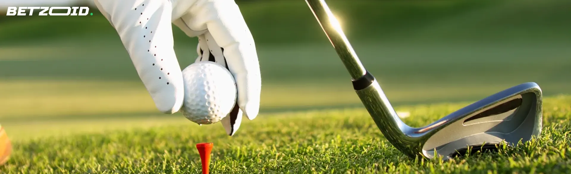 A golfer's hand places the ball for the shot.